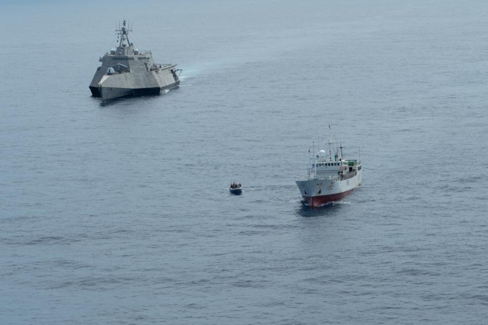 PACIFIC OCEAN (Aug. 18, 2022) – Independence-variant littoral combat ship USS Oakland (LCS 24) stations behind a fishing vessel while Tactical Law Enforcement Team Pacific Coast Guardsmen conduct an Oceania Maritime Support Initiative (OMSI) vessel compliance boarding, Aug. 19, 2022. Oakland is deployed in support of the Oceania Maritime Support Initiative, a secretary of defense program leveraging Department of Defense assets transiting the region to increase the Coast Guard’s maritime domain awareness, and law enforcement operations in Oceania. (U.S. Navy photo by Mass Communication Specialist 2nd Class Ian Zagrocki)