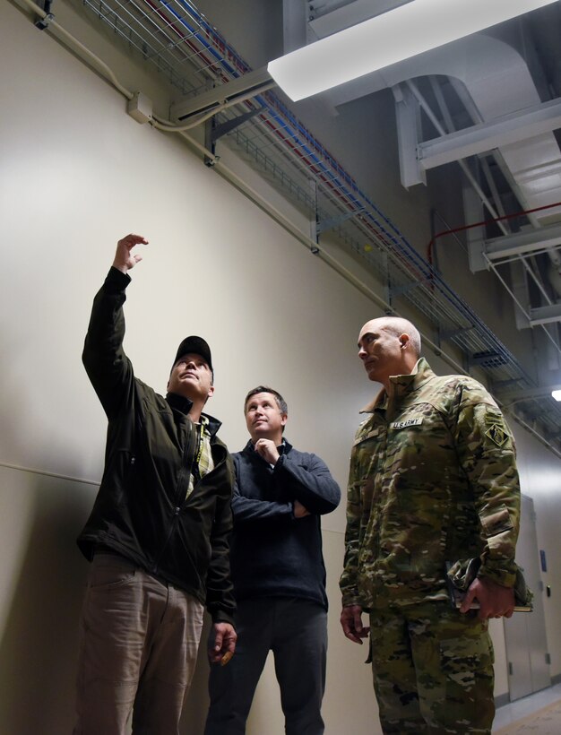 Mike Doty, electrical engineer, USACE Alaska District, points out how congested the area is above the ceiling beams in the Long Range Discrimination Radar (LRDR) power plant during a tour of the facility at Clear Space Force Station with Bret Styers, senior program manager for the Ballistic Missile Defense Mandatory Center of Expertise at the U.S. Army Engineering and Support Center, Huntsville, and Col. Sebastien P. Joly, Huntsville Center commander, on August 16. The additional structural supports needed to protect the building and its mechanical and electrical components from blasts created an engineering challenge for USACE during the design phase, said Doty. (Photo by Kristen Bergeson)