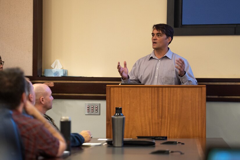 Jeremy Zidek speaks from a podium in front of Alaskan Command staff and other participants of Arctic Resolve 2022.