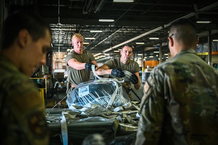 Staff Sgt. Jordan White and Senior Airman Kyle Johnson, air transportation for the 155th Air Refueling Wing, Nebraska Air National Guard, place a net on a loading pallet Aug. 18, 2022, during annual training at Travis Air Force Base, Calif. The 155th Logistics Readiness Squadron sent Airmen to Travis AFB for exposure to new aircraft and deployment readiness training.