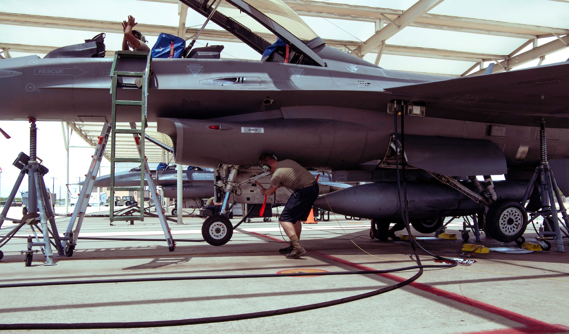 Crew chiefs from the 149th Maintenance Group perform a landing gear swings operations check on an F-16 Fighting Falcon