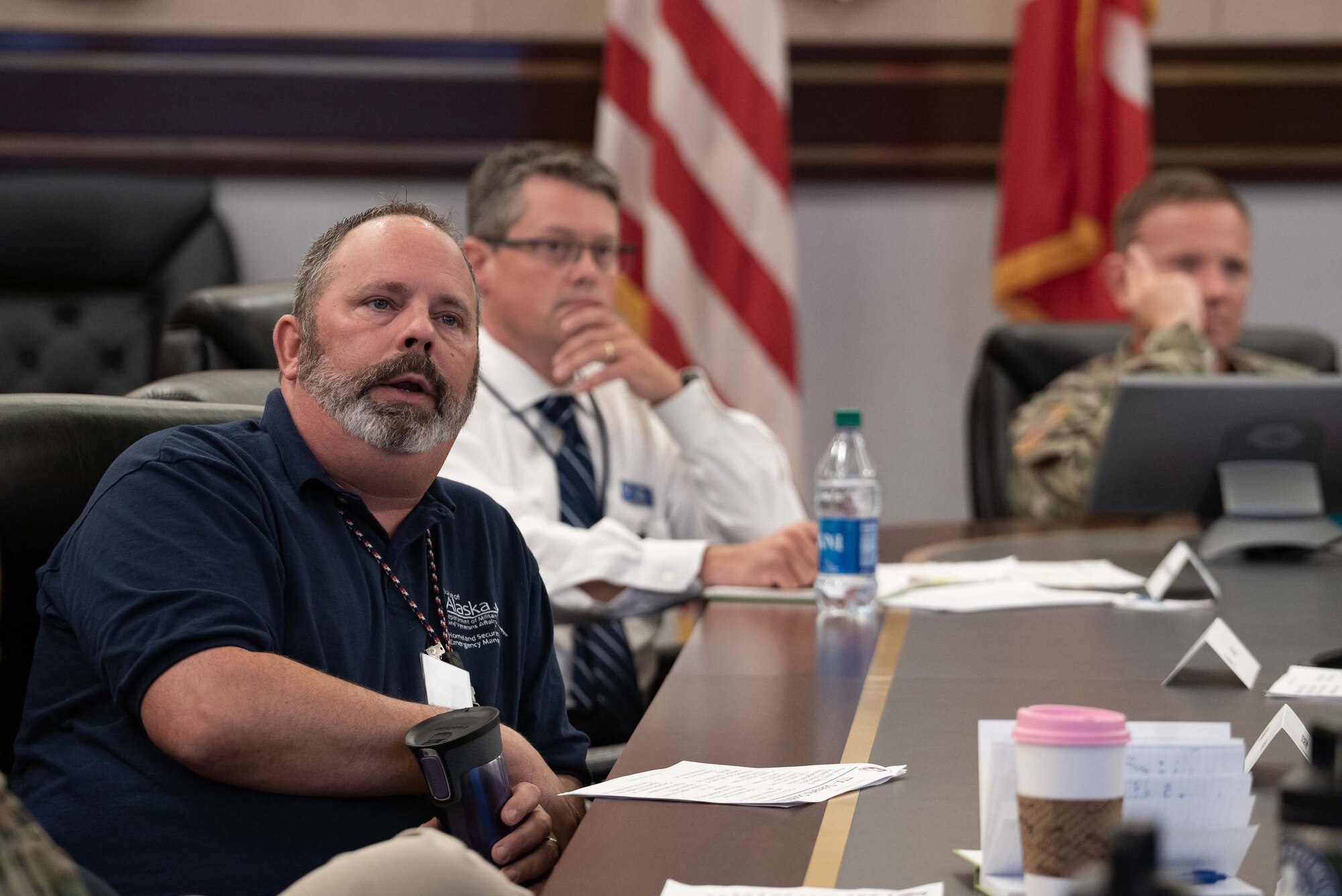 Bryan Fisher looks toward a projected slideshow and explains information to other individuals at a conference table