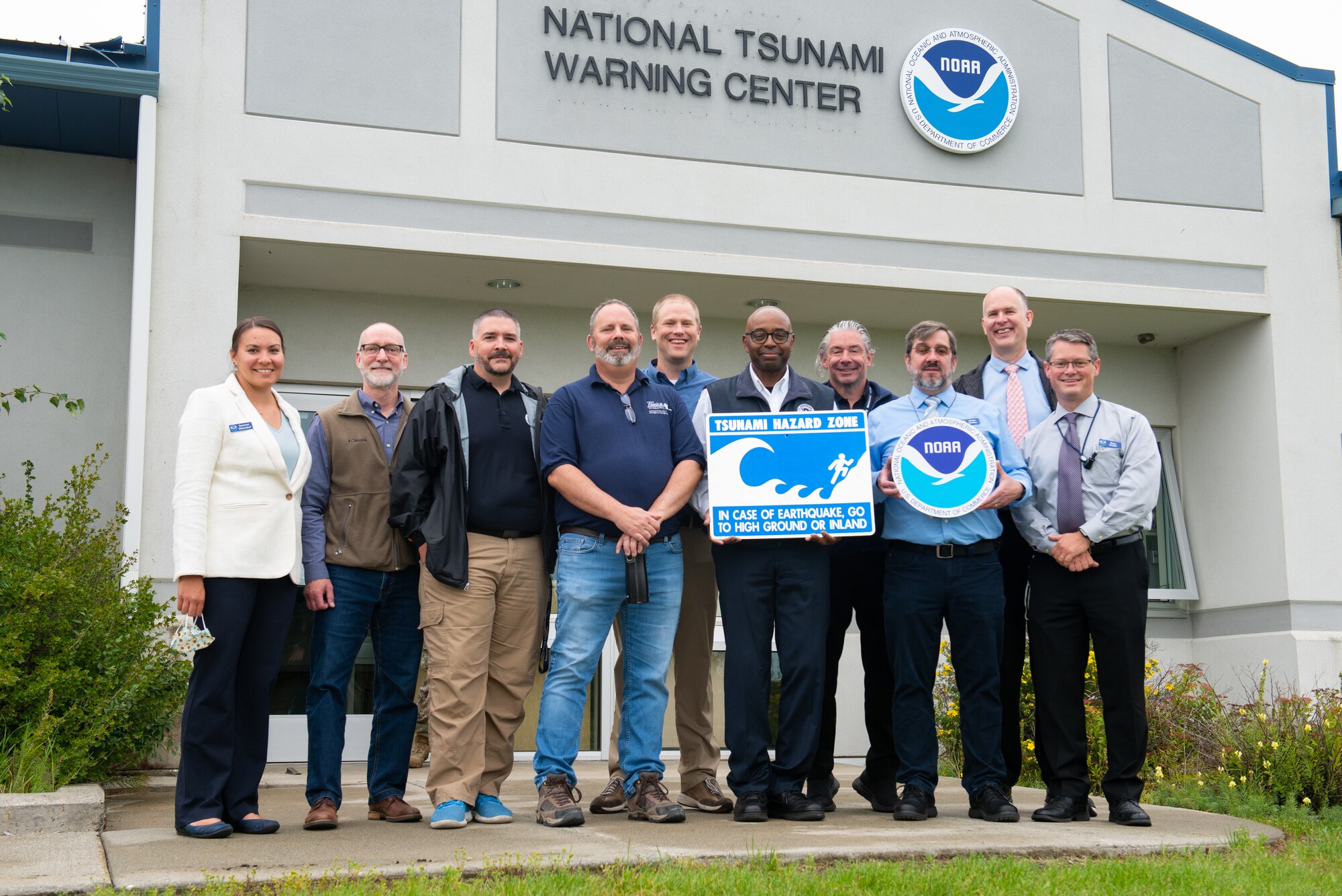 Members from the National Oceanic and Atmospheric Association, the Federal Emergency Management Agency, and other emergency response organizations pose for a photo in front of the National Tsunami Warning Center