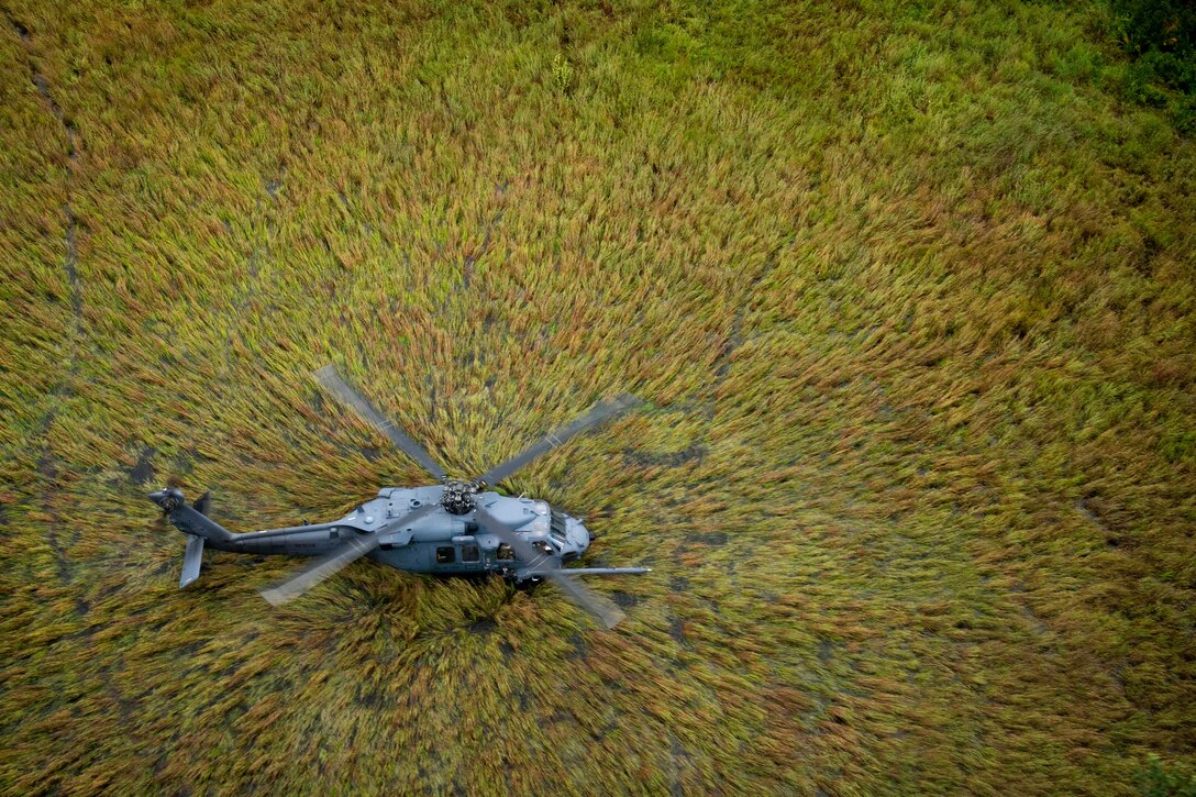 A helicopter flies over trees as seen from above.