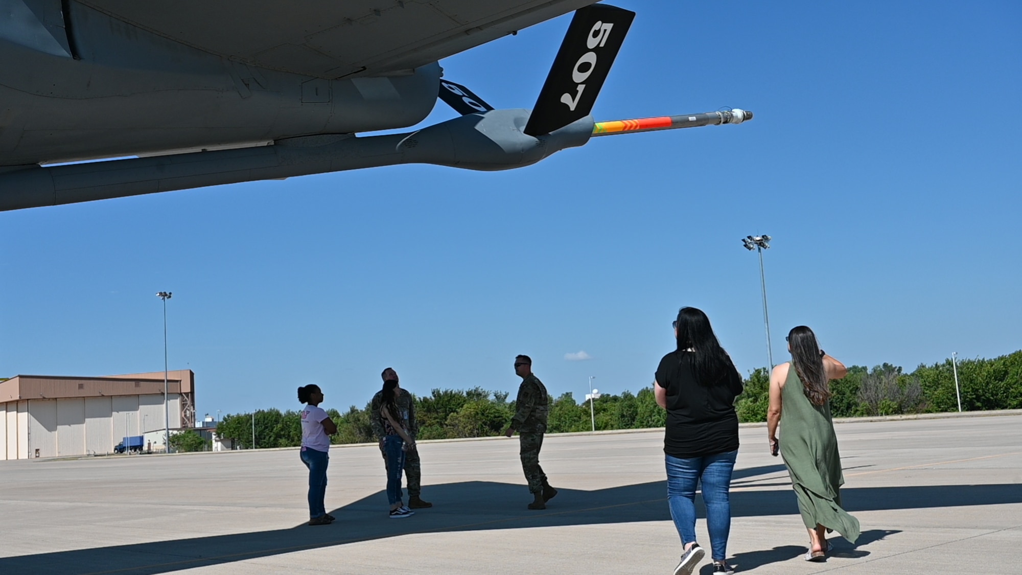 people stand under the tail of a plane
