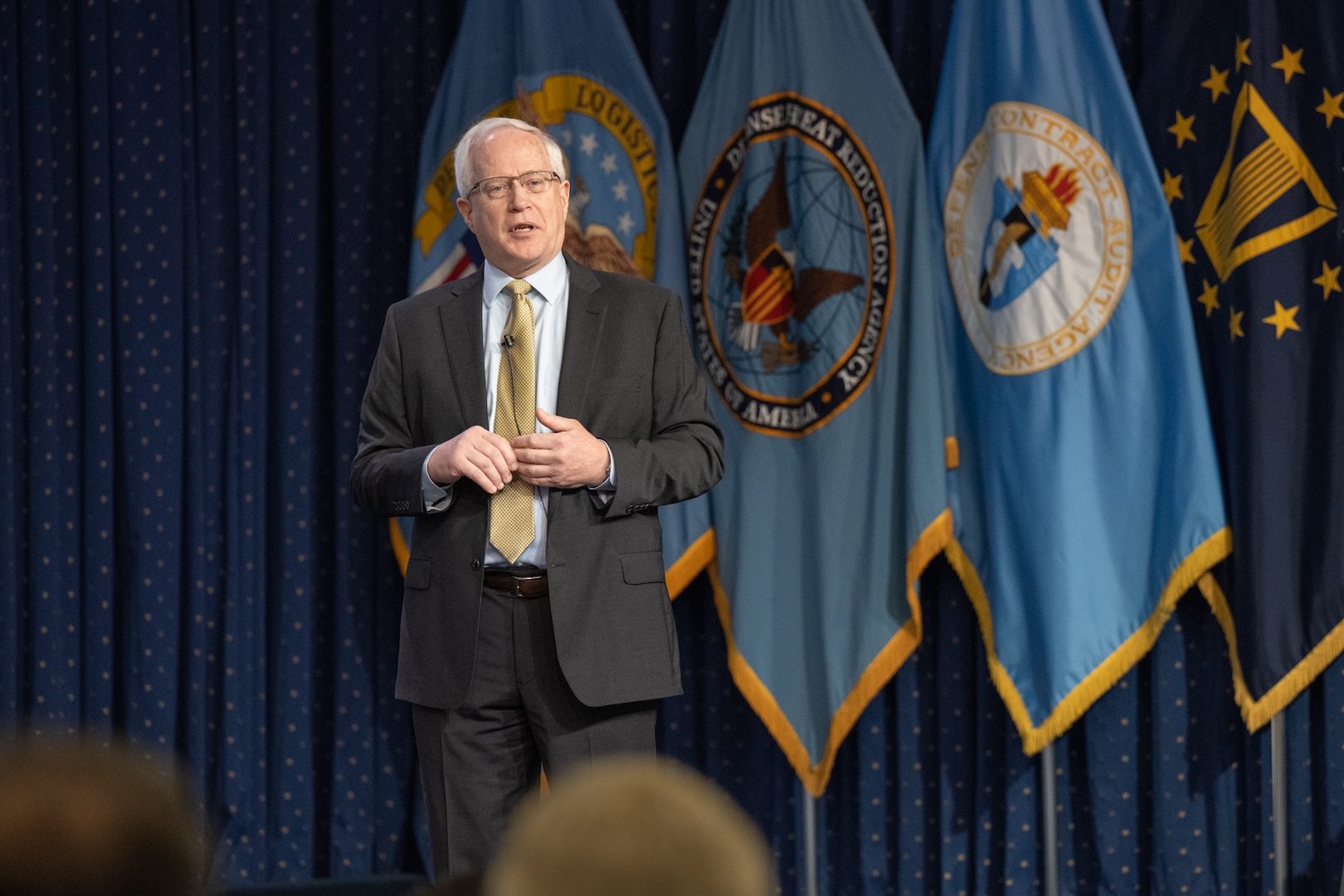 A man gives remarks on a stage.