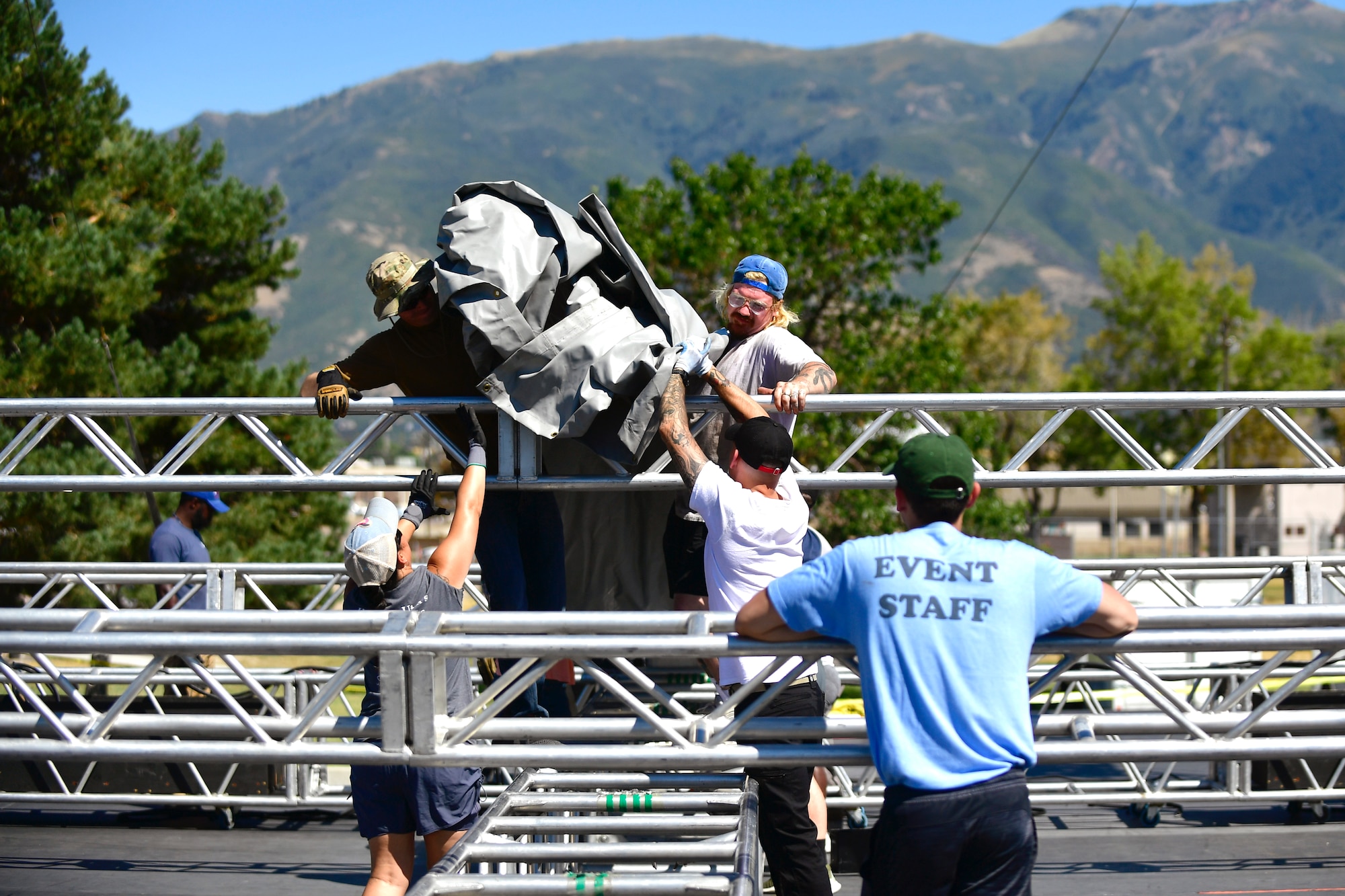 Volunteers assist Air Force Entertainment Service workers while setting up the rock festival concert stage Aug. 26, 2022, at Hill Air Force Base, Utah. The annual concert is held to boost morale and resiliency for the military and civilian workforce and their families, and was coordinated by the 75th Force Support Squadron through the Air Force Entertainment Service. (U.S. Air Force photo by Todd Cromar)