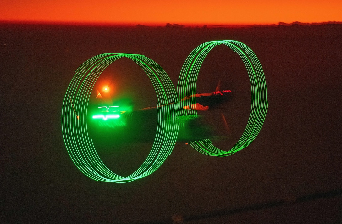 The rotors of an airborne aircraft creates green rings at night.