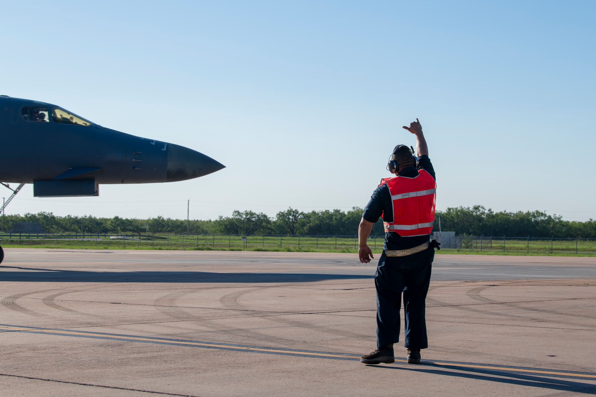 MSgt Kevin Minnick, from the 489th Maintenance Squadron, gives the B-1B Lancer aircrew a hand signal at Dyess Air Force Base, Texas Sept. 7th, 2022, before their take-off in support of a Bomber Task Force mission. Strategic comber missions, such as the BTFs, enhance the readiness and training necessary to respond to any potential crisis or challenges across the globe. (U.S. Air Force photo by Senior Airman Mercedes Porter)
