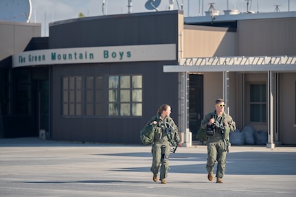 A photo of 1st Lt. Kelsey Flannery, an F-35A Lightning II pilot, and Capt. Jake Dubie, an instructor pilot, both assigned to the 134th Fighter Squadron of the Vermont Air National Guard's 158th Fighter Wing, head to their jets for a training mission from South Burlington Air National Guard Base, Vermont, Sept. 7, 2022. Flannery, who is the Air National Guard's first female F-35 pilot, made her first flight with the 158th after returning from three years of flight training. (U.S. Air National Guard photo by Master Sgt. Ryan Campbell)