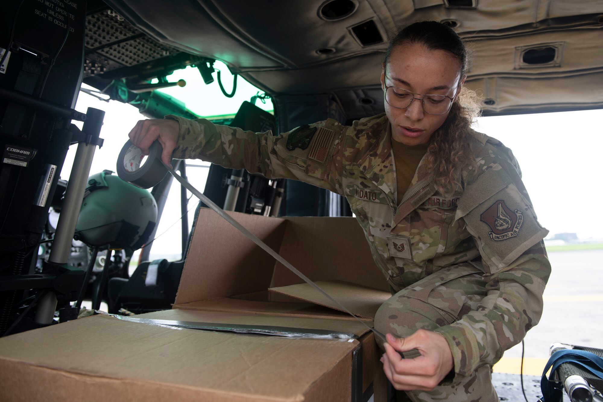 Tech. Sgt. Alexandra Vidato, 459th Airlift Squadron instructor flight engineer, tapes a box of simulated humanitarian aid prior to takeoff for a Tokyo Metropolitan Government hosted disaster preparedness and response drill at Tokyo Rinkai Disaster Prevention Park, Japan, Sept. 3, 2022. Taking off from Yokota Air Base, the 459th utilized a UH-1N Iroquois helicopter to deliver mock humanitarian aid after a simulated natural disaster. (U.S. Air Force photo by Tech. Sgt. Joshua Edwards)