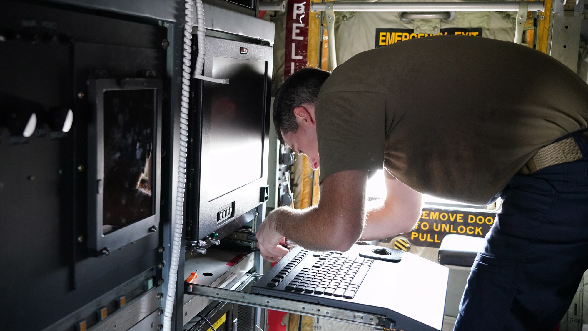 Shows a male Airman reattaching the keyboard for the new computer system on the military aircraft.