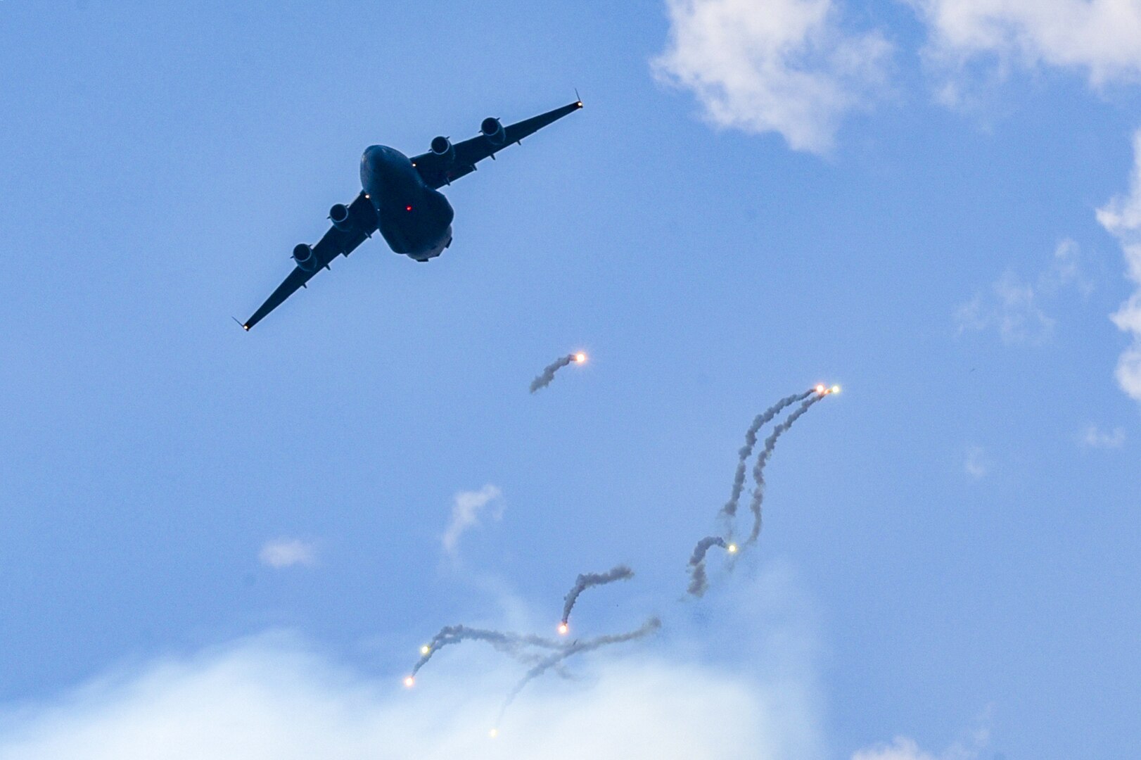 A C-17 Globemaster III aircraft from the 305th Air Mobility Wing and its associate reserve unit, the 514th Air Mobility Wing, based at Joint Base McGuire-Dix-Lakehurst, New Jersey,  practices flying a resupply mission into a hostile location while responding to simulated surface to air missiles at Bollen Range on Fort Indiantown Gap, Pennsylvania, Aug. 22, 2002. The crew of the C-17 included two 111th Attack Wing personnel who helped integrate MQ-9 support.