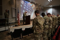 Deploying Soldiers bow their heads during the benediction at their deployment ceremony.