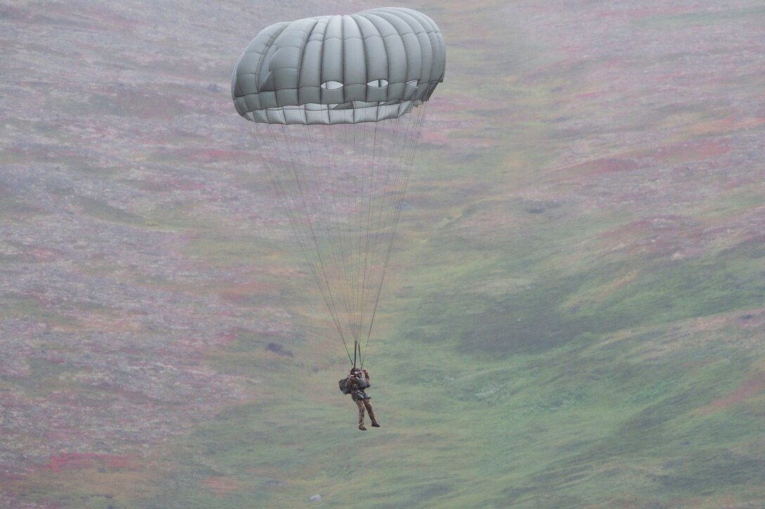 An airman parachutes down to the ground.