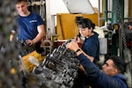 Coast Guard Petty Officers Third Class Third Class Joanalicia Ramirez and Miguel Caceres, both machinery technicians, work together with their unit to build an engine on a cutter moored at Base Portsmouth, Nov. 16, 2021, in Portsmouth, Virginia. The unit, called the Maintenance Augmentation Team, or MAT, provides mechanical and maintenance support for the cutters in the area. (U.S. Coast Guard photo by Petty Officer Third Class Emily Velez)