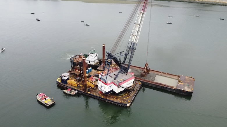 A clamshell dredge and barge sits in the Rogue River near the Port of Gold Beach, Ore., Aug. 31. Without consistent dredging by the U.S. Army Corps of Engineers (Corps), the port could lose out on recreation income sprouting from upwards of 35,000 visitors per year for jet boat tours and around 75-100 fishing boats a day (at least 10 fishermen in the distance), according to port officials. (U.S. Army photo by Ben Rogers)