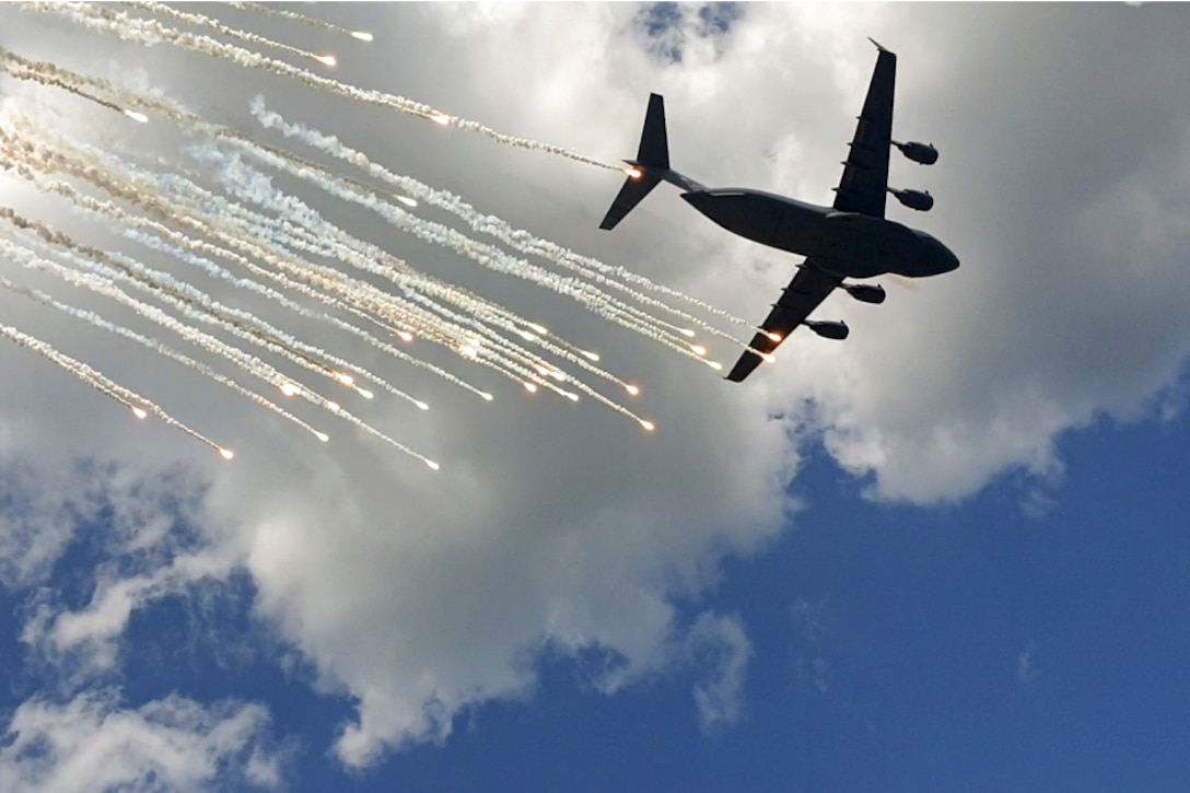 An aircraft flies near flares as seen from below.