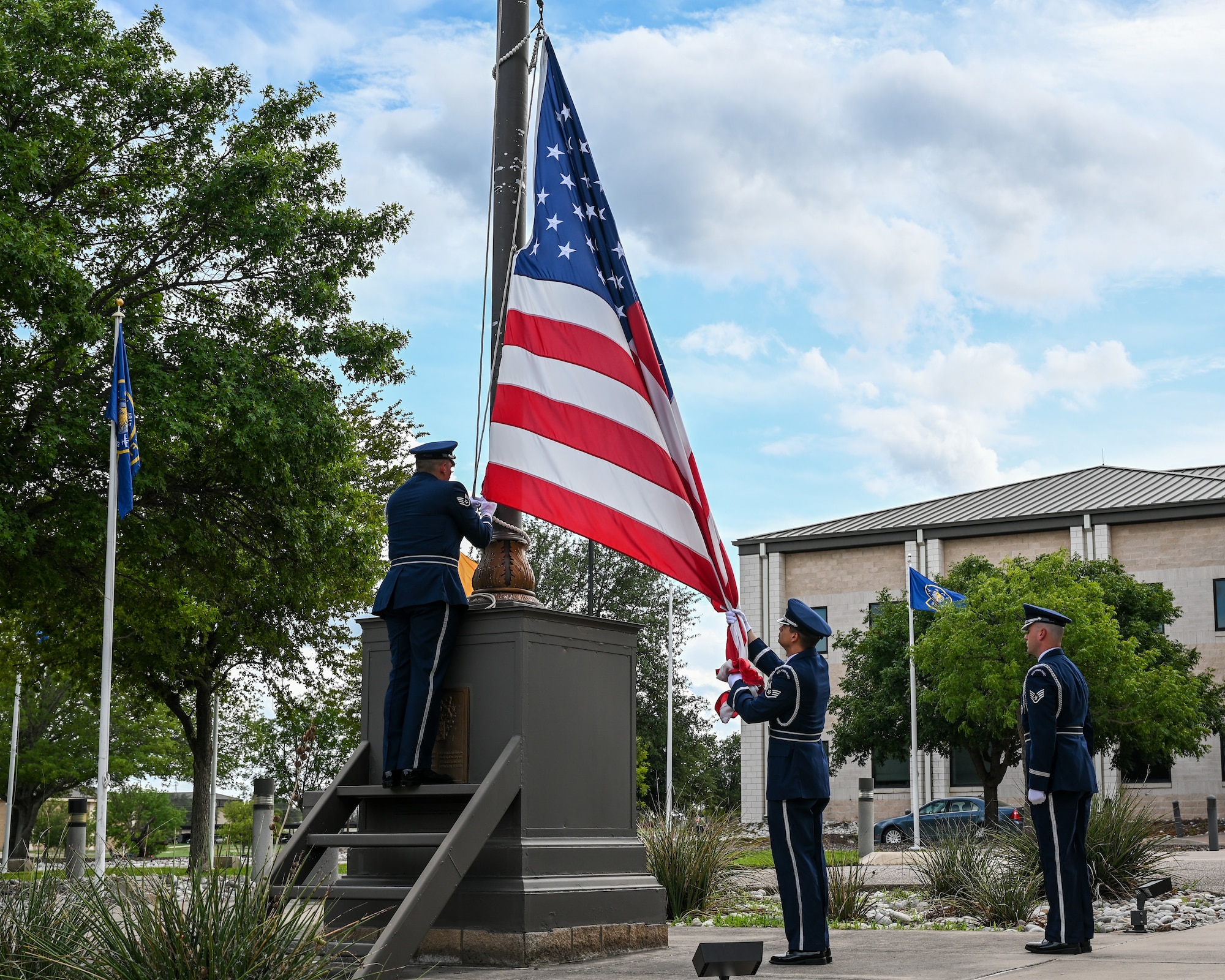 U.S. Air Force Staff Sgt. Jesus Vega German, 47th Force Support Squadron base honor guard program manager, left, lowers the American flag to fellow honor guard members during a retreat ceremony at Laughlin Air Force Base, Texas, on Sept. 2, 2022. The 85th FTS celebrated its 50th anniversary at Laughlin which ended with a retreat ceremony. (U.S. Air Force photo by Airman 1st Class Keira Rossman)