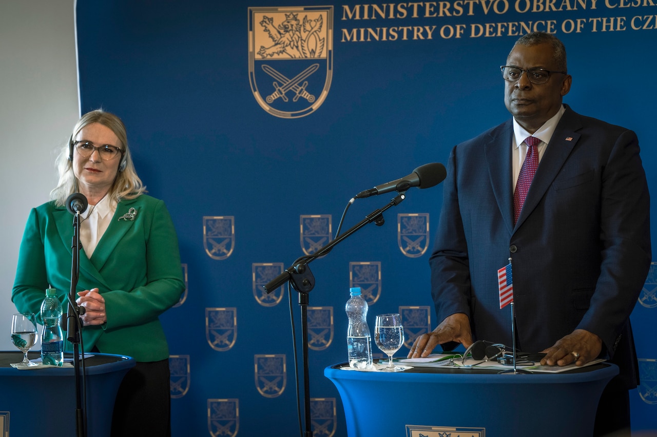 Secretary of Defense Lloyd J. Austin III and another official stand at twin lecterns.