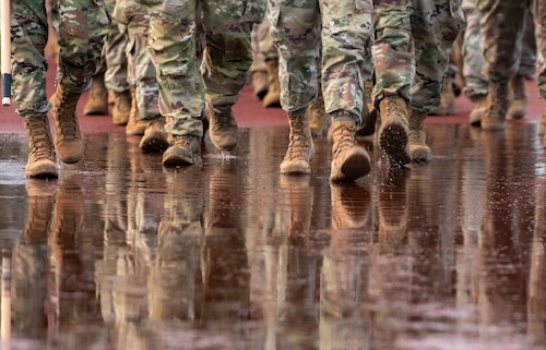 Boots reflect in water on a track during a ruck march