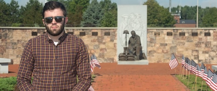 John Brutzman, the substance abuse prevention coordinator for the Vermont National Guard, stands in front of the Fallen Heroes Memorial at Camp Johnson, Vermont, on Sept. 8, 2022. The 22 flags at the memorial represent the approximately 22 veterans lost to suicide every day. Brutzman, a native of Montclair, New Jersey, also serves as a suicide prevention coordinator as needed. (U.S. Army National Guard photo by Don Branum)