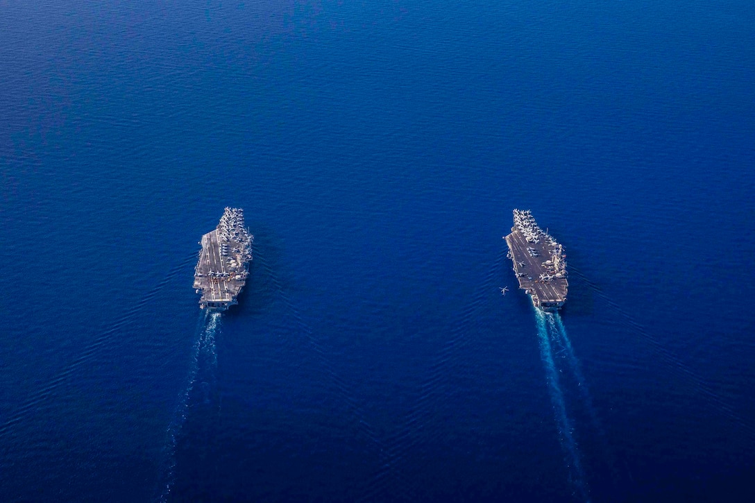 Two ships travel through waters side by side.