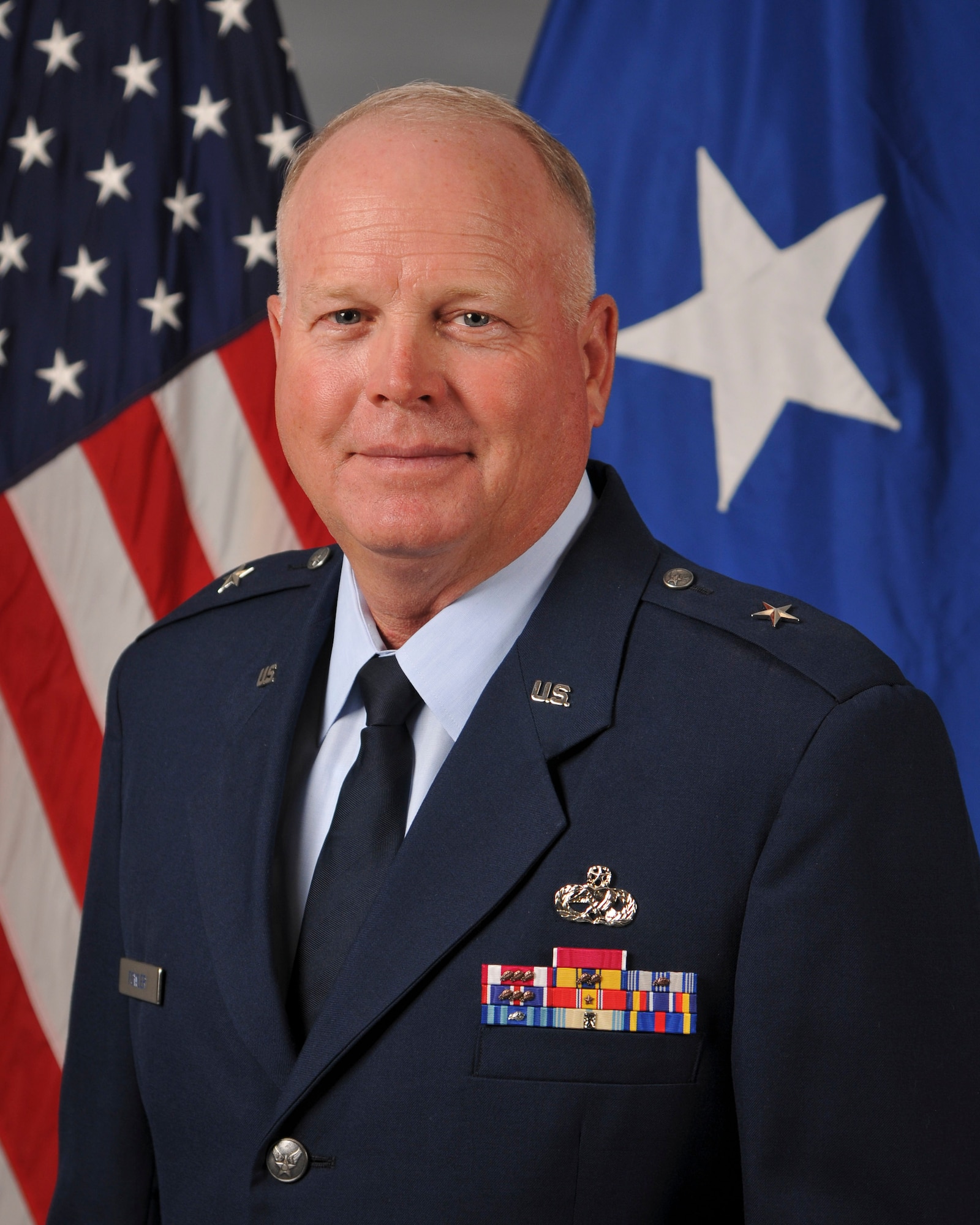 An Air Force general in uniform against a background of flags