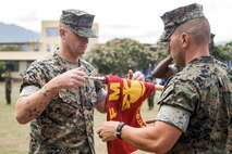 U.S. Marine Corps 1st Sgt. Robert Adams, left, Marine Wing Communications Squadron 18, Bravo Company 1st Sgt., and Maj. Scott Siska, right, company commander, MWCS-18, Bravo Co, unfurl the company colors during the MWCS-18, Bravo Co activation ceremony, Marine Corps Base Hawaii, Sept. 1, 2022. The company activated in accordance with the Marine Corps progression towards Force Design 2030. (U.S. Marine Corps photo by Cpl. Samantha Sanchez)