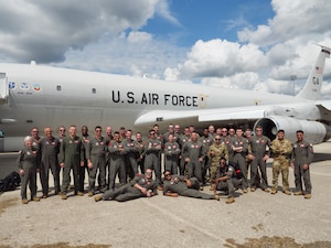 Photo shows group of Airmen standing in front of plane for photo