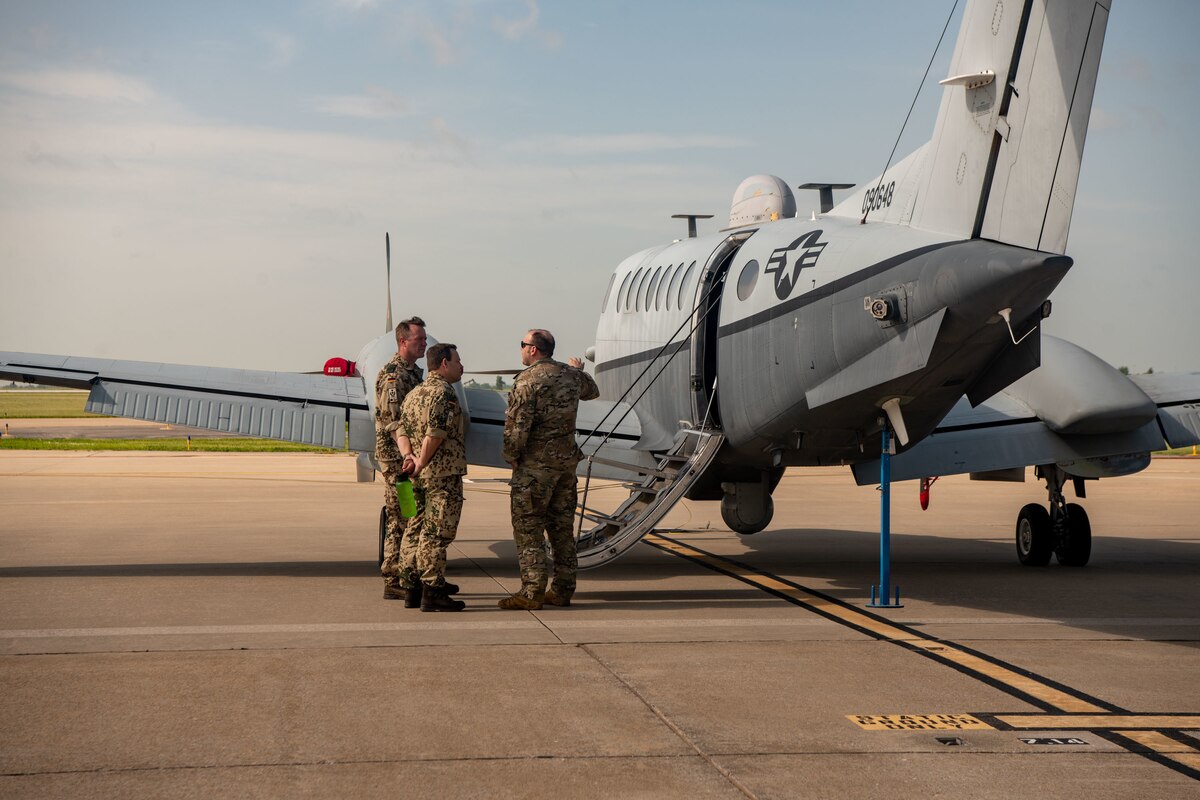 German Air Force Lt. Col. Alex Frick, left, mission support squadron commander of Helicopter Wing 64, Laubheim, and German Air Force Maj. Alex Schroth, middle, troop driver with Air Command, Berlin, listen as U.S. Air Force Capt. Patrick Devito, combat systems officer with the 137th Special Operations Wing, Oklahoma National Guard, gives a tour of the MC-12W during a Military Reserve Exchange Program visit June 15, 2022, Oklahoma City. The program supports reserve force exchanges between NATO nations where Reservists and Guardsmen from the U.S. visit and host personnel from a foreign country.