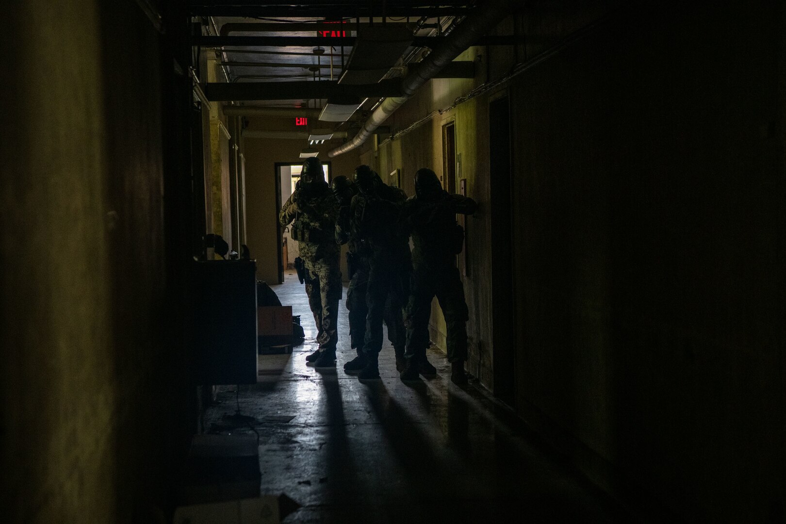 airmen tactically move through a darkened hallway