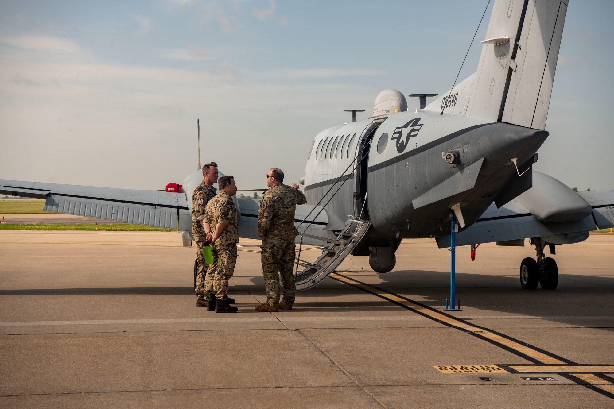 German Air Force Lt. Col. Alex Frick, left, mission support squadron commander of Helicopter Wing 64, Laubheim, and German Air Force Maj. Alex Schroth, middle, troop driver with Air Command, Berlin, listen as U.S. Air Force Capt. Patrick Devito, combat systems officer with the 137th Special Operations Wing, Oklahoma National Guard, gives a tour of the MC-12W during a Military Reserve Exchange Program visit June 15, 2022, Oklahoma City. The program supports reserve force exchanges between NATO nations where Reservists and Guardsmen from the U.S. visit and host personnel from a foreign country.