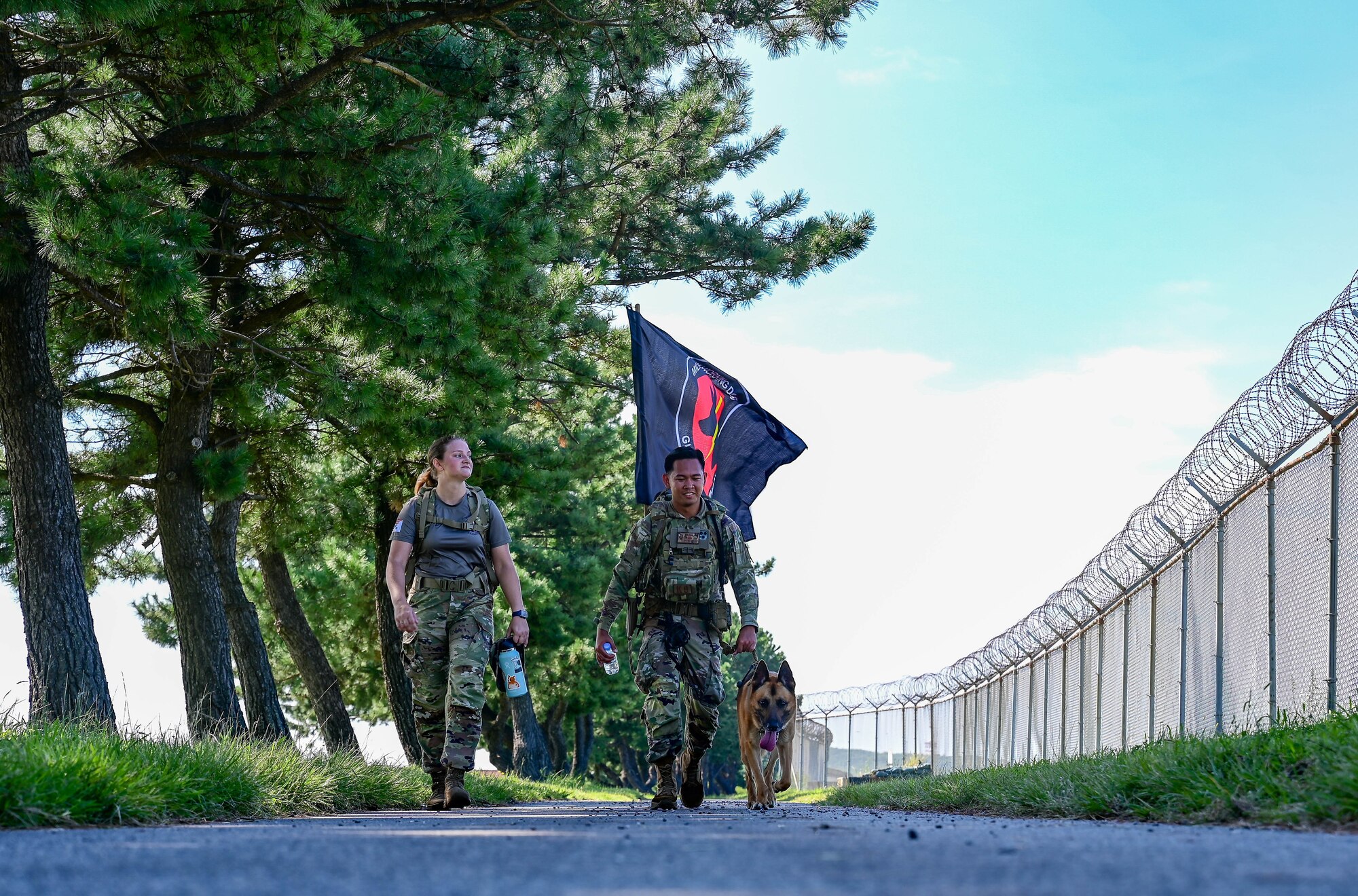 Senior Airman Jonathan Casazza Barbosa, 8th Security Forces Squadron military working dog handler, walks with the military working dog flag during a 9/11 remembrance ceremony at Kunsan Air Base, Republic of Korea, Sept. 8, 2022. Over 300 dogs assisted the search and rescue efforts after the terrorist attacks on Sept. 11, 2001. (U.S. Air Force photo by Senior Airman Shannon Braaten)