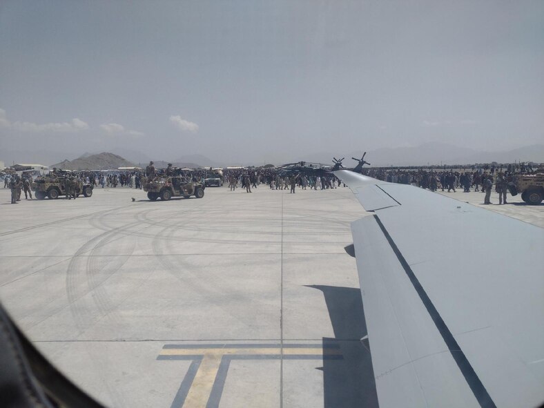 The wing of a U-28 Draco aircraft in foreground with crowd in background.