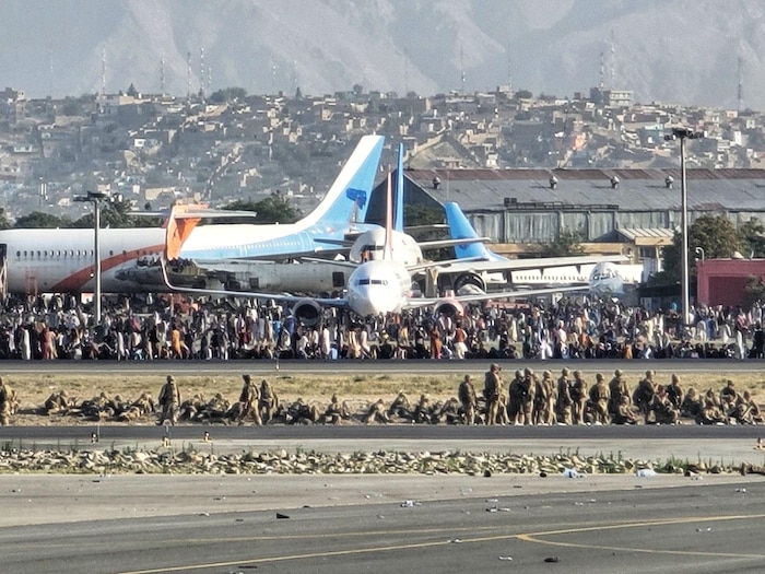 Aircraft and mountains in background and flight line with Airmen in foreground.