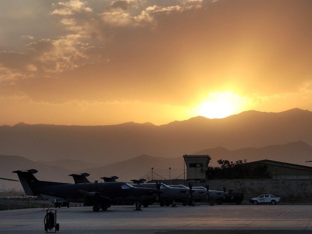 U-28 Draco aircraft sit on the flight line, mountains and sunrise in background.