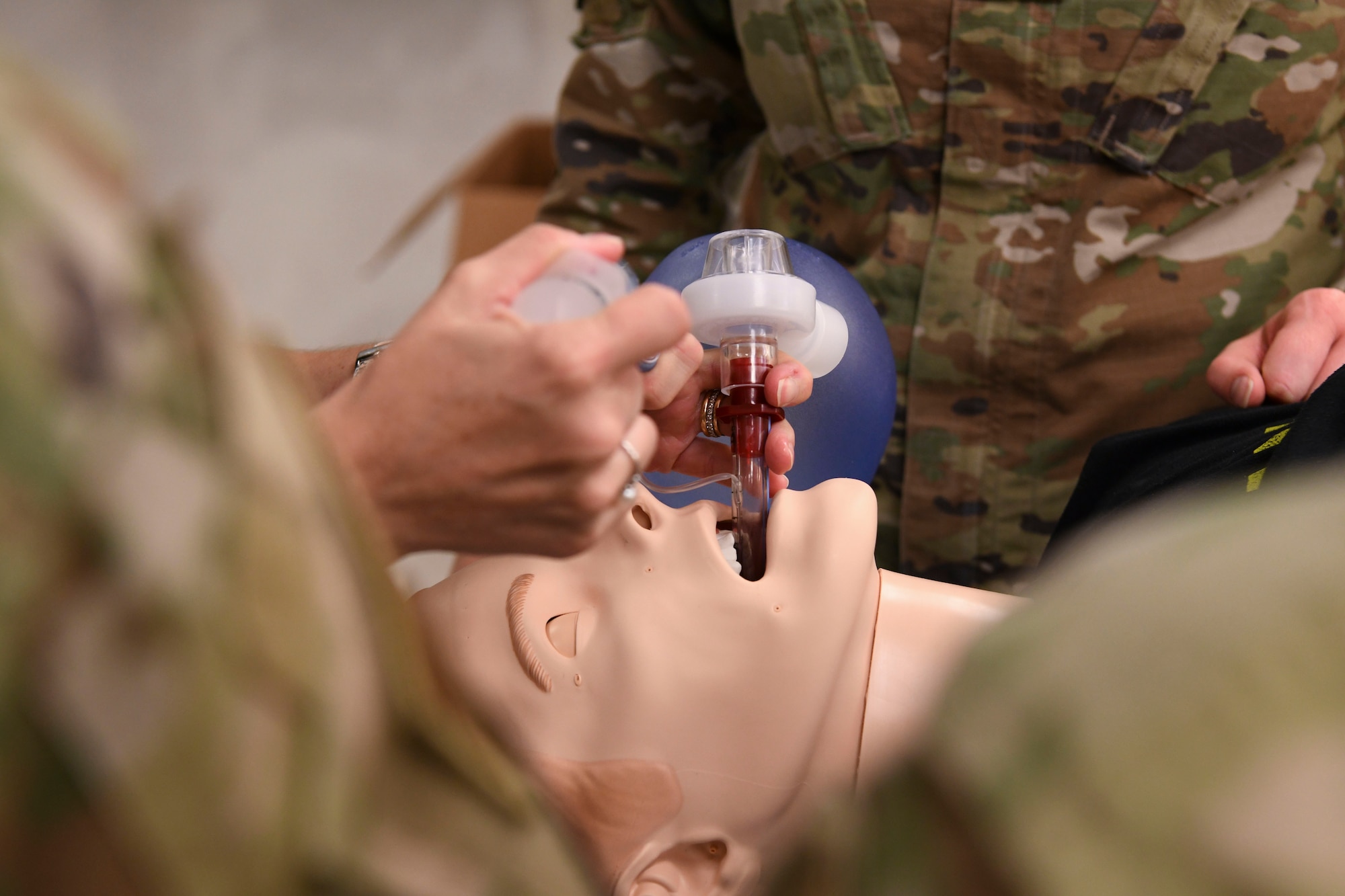 U.S. Air Force Airmen practice placing an airway adjunct device used in emergency field treatment on a training mannequin