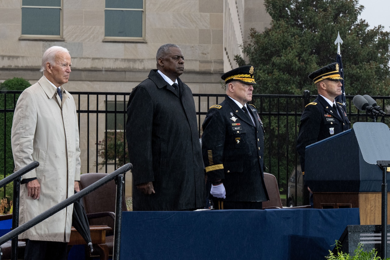 Four men stand at attention on a stage at the Pentagon.