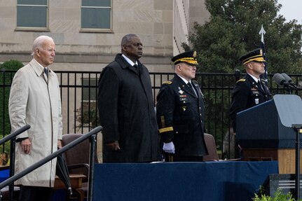Four men stand at attention on a stage at the Pentagon.