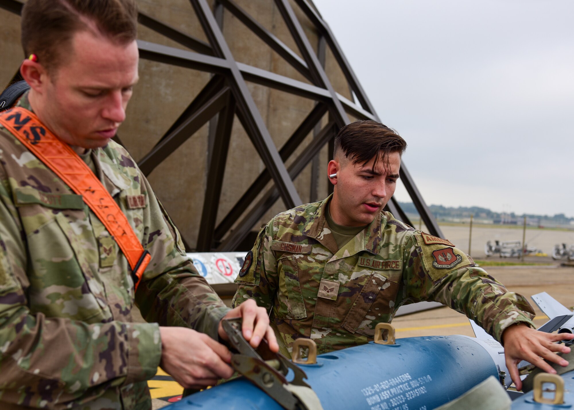 Senior Airmen Miles Scott and August Gusman, 555th Fighter Generation Squadron ammo crew chiefs, from the 31st Fighter Wing, Aviano Air Base, Italy, loosen the straps on missiles before it is loaded onto aircraft