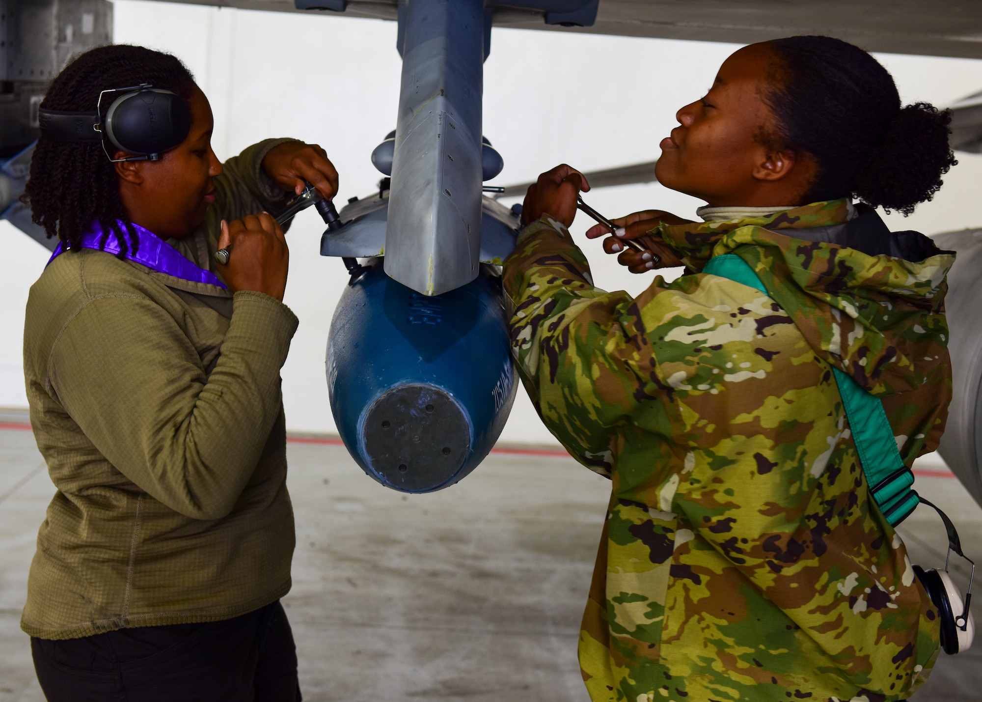 U.S. Air Force Staff Sgt.’s Akeia Williams, 555th Fighter Generation Squadron weapons loading crew member and Samill Harkness weapons loading crew chief from the 31st Fighter Wing, Aviano Air Base, Italy, perform a locking mechanism to secure a missile onto an F-16C Fighting Falcon