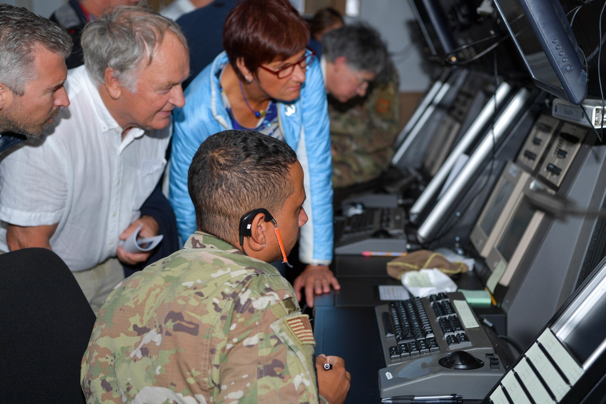 U.S. Air Force Staff Sgt. Tory Jinks, center, 86th Operation Support Squadron watch supervisor, explains the functions of air traffic control monitors and how they are used to complete the mission at Ramstein Air Base, Germany, Sept. 9, 2022.