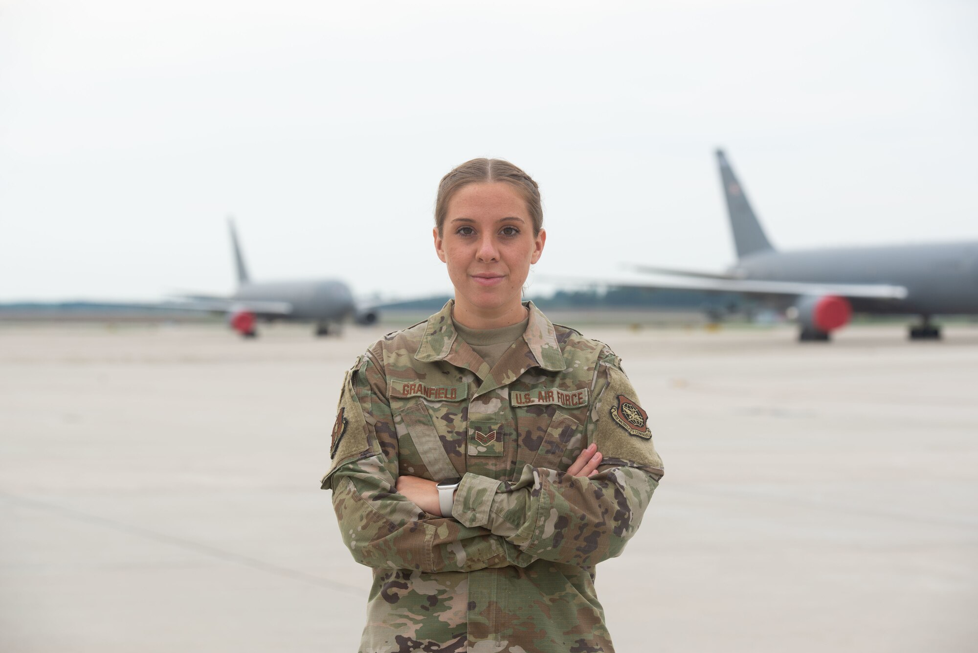 Airman Granfield stands on the flight line in front of a KC-46.