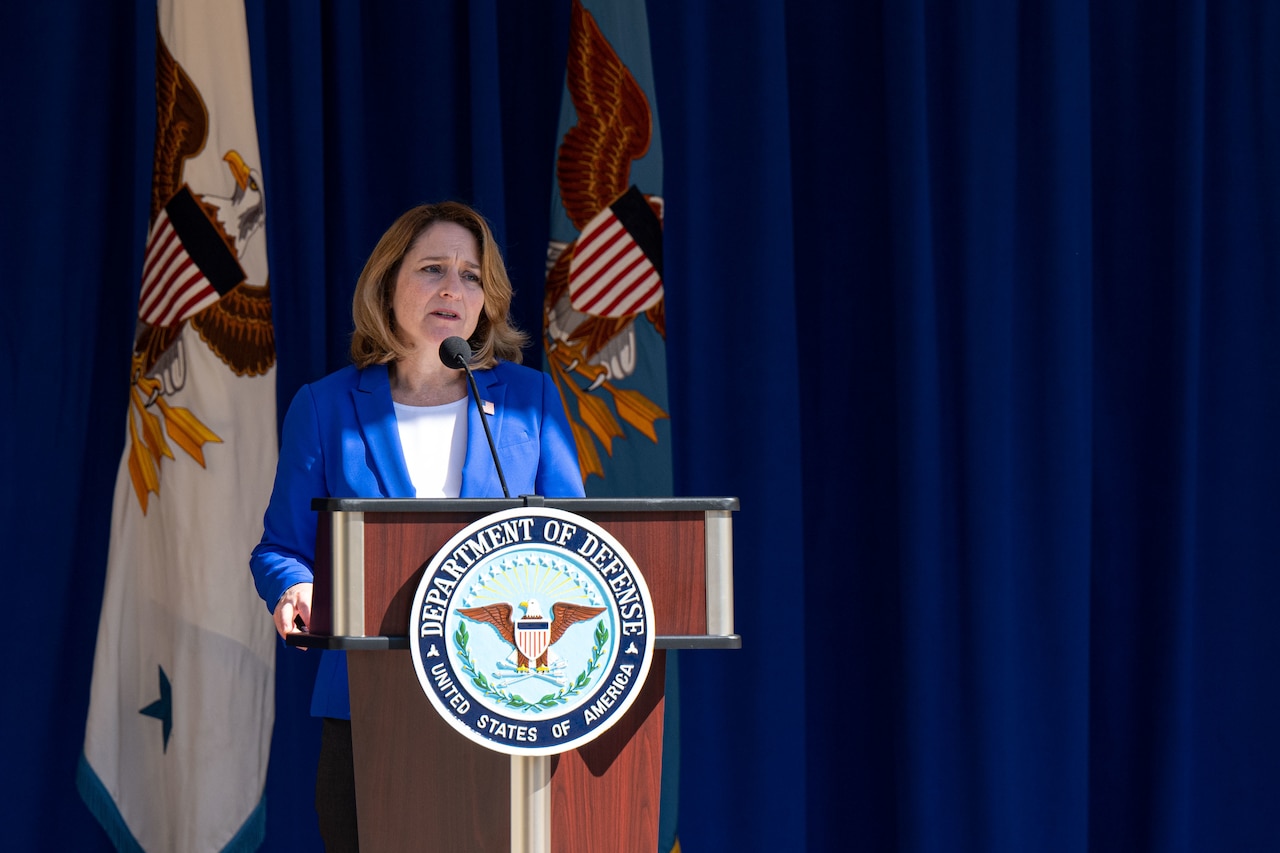 A woman speaks in front of a podium.