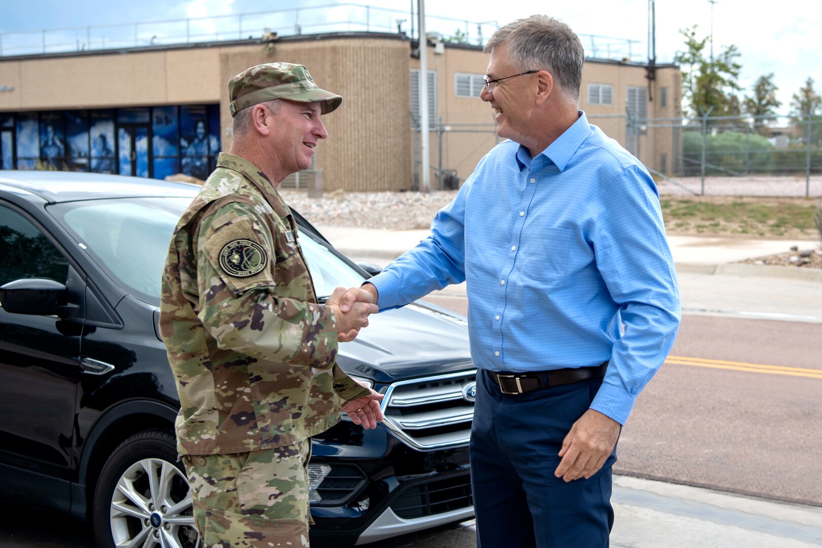 Military man in uniform shakes hands with man in business casual attire