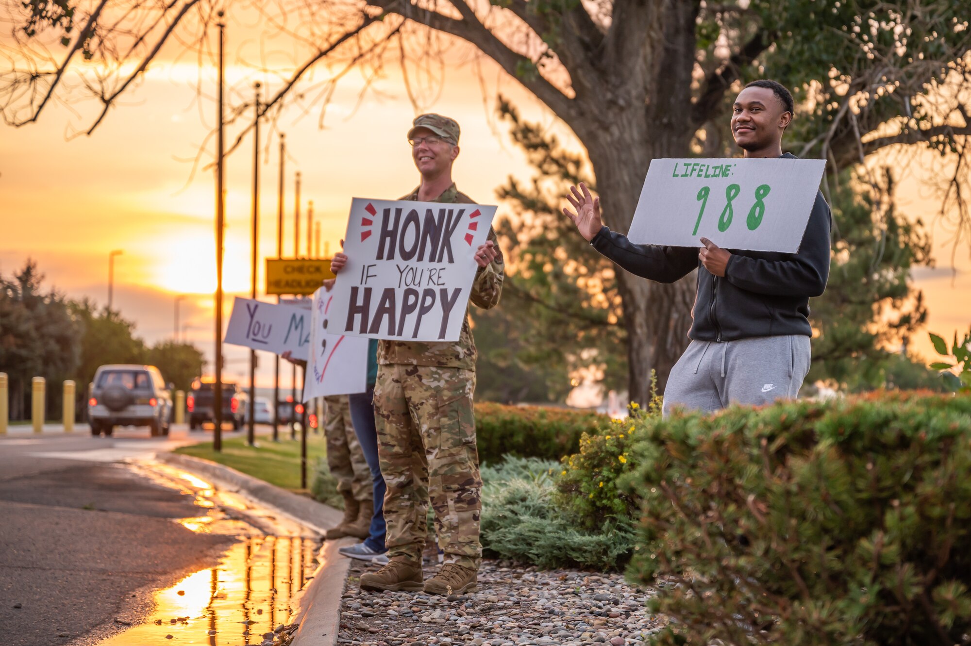 Chief Master Sgt. Michael Becker, center, 341st Missile Wing command chief, and Airmen throughout Malmstrom hold homemade signs during morning traffic Sept. 9, 2022, at Malmstrom Air Force Base, Mont.
