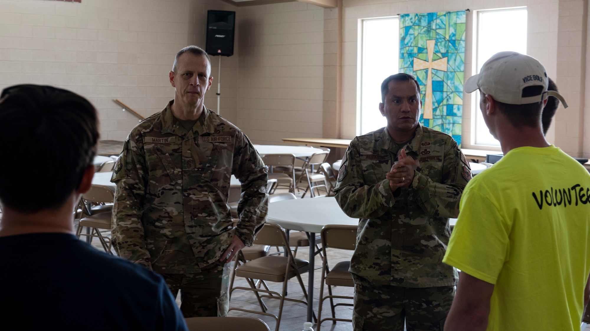 Two men in green ocps talk to a group of people.