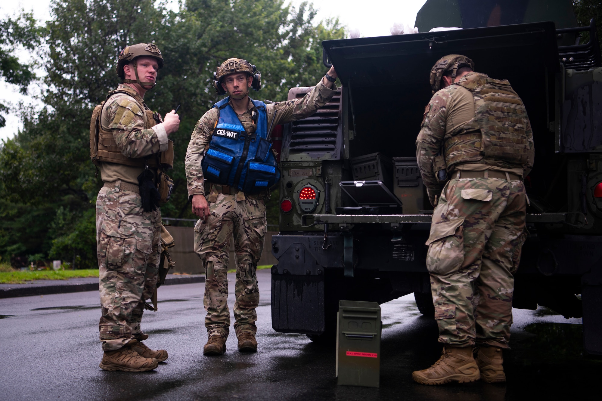 U.S. Air Force members gather equipment at the trunk of a Humvee.