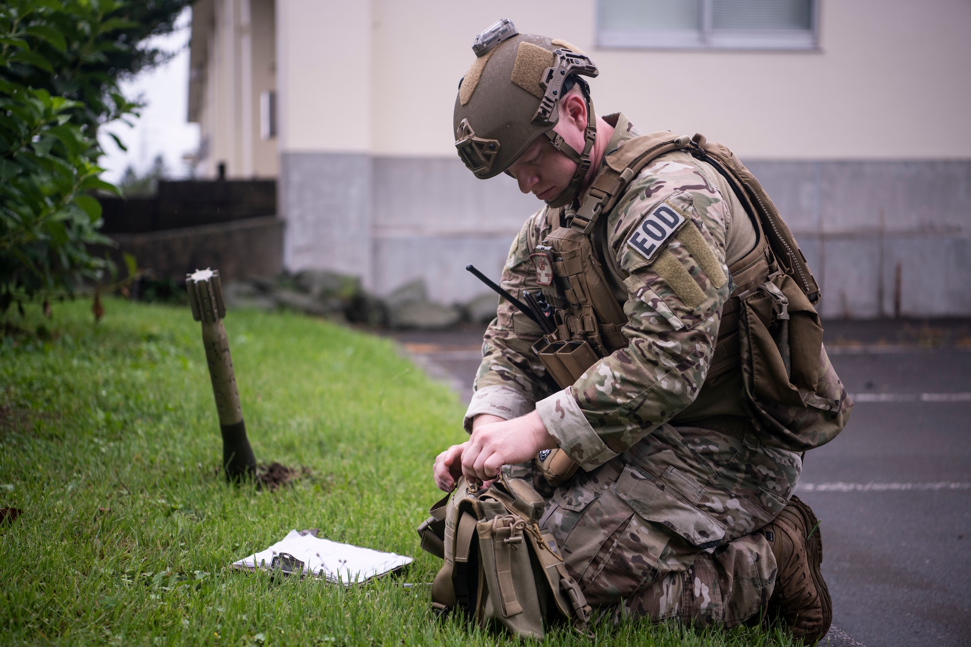 A U.S. Air Force member kneels down next to equipment on the ground.